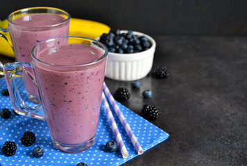 Smoothie with banana, blackberries and blueberries on a black ba