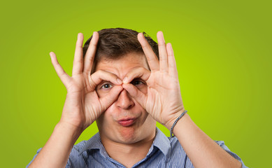 Close up of a doubtful guy with gesture of observe on green background