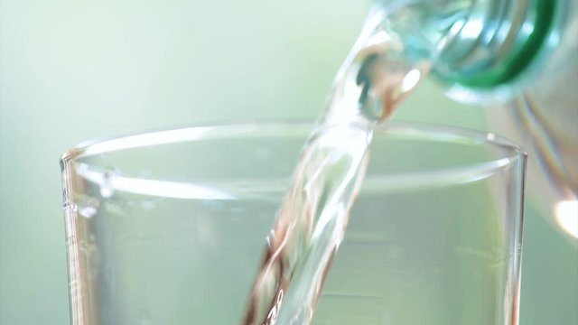 Pouring glass of fresh mineral water fullHD video. Close-up glass and plastic bottle of cool soda water on abstract light background.