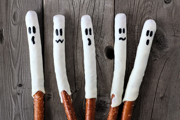 Group of Halloween ghost, candy dipped pretzel rods on aged wood background