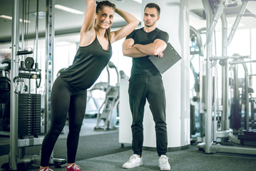 Personal fitness trainer with his client in gym.