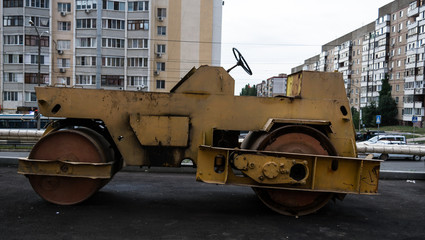 The old machine paver. City, multi-storey building in the backgr