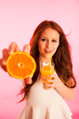 Woman drinking orange juice smiling showing oranges. Young beaut