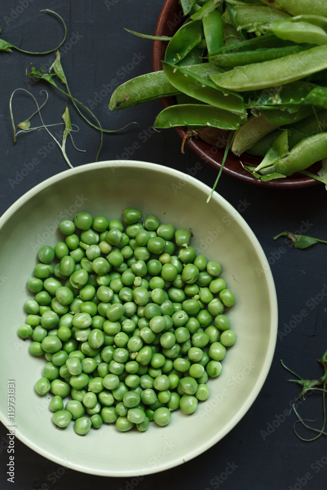 Wall mural Plate of fresh peeled peas on black table. Rustic style