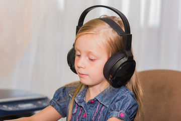 portrait of a beautiful girl with long hair in big headphones. she closely involved in the computer...