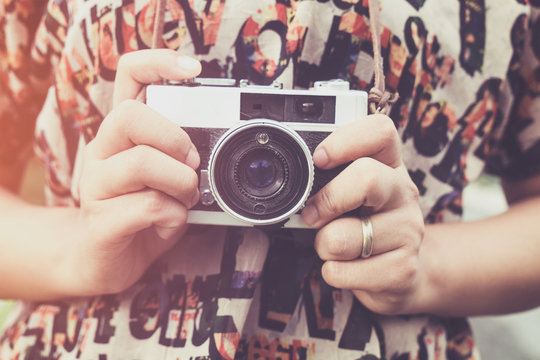 Close-up shot of woman hand holding retro camera. young hipster girl photographer with film camera - vintage filter color effect style