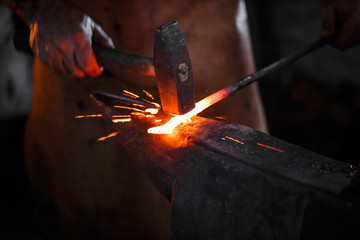 Blacksmith manually forging the molten metal - obrazy, fototapety, plakaty