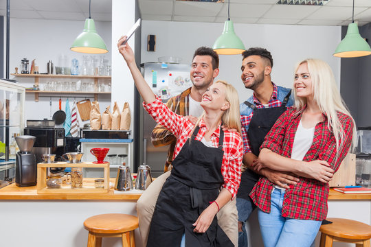 People taking selfie friends pictures drinking coffee shop with barista sitting at bar counter, mix race men hold smart phone woman happy smile