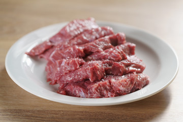 raw fresh sliced beef for beefsteaks in plate on kitchen table