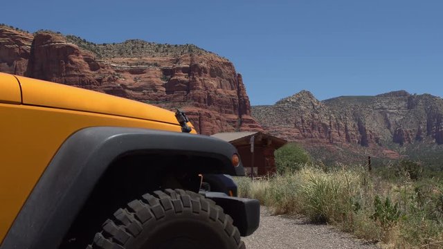Offroad SUV parked in front of red rock mountains of Sedona, strong yellow color of the safari jeep stands out against nature scenic