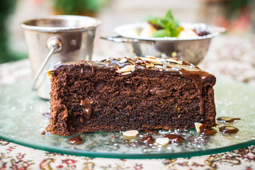 Piece of chocolate cake with fruit and ice cream is on the glass tray on the table