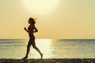 Fototapeta na wymiar Girl runs along the beach at sunset