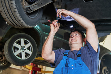 Automobile mechanic checks car suspension in service station