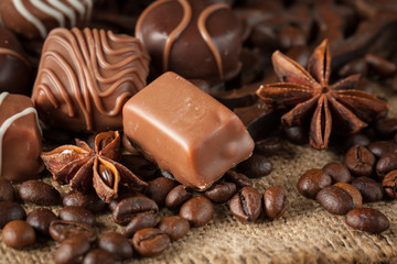 Assortment of dark, white and milk chocolate stack, chips. Chocolate and coffee beans on rustic wooden sacking background. Spices, cinnamon. Selective macro focus. Chocolates background. Sweets