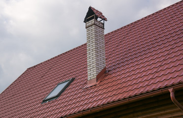 Roof with skylight and chimney over dark cloudy sky