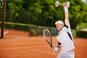 Happy tennis player with goblet and racket