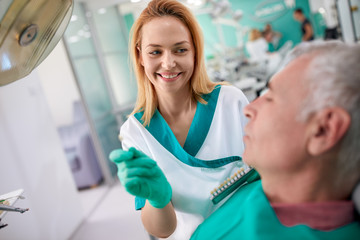 Fototapeta premium Female dentist shows to patient closest color of teeth for dentu