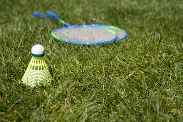 Badminton rackets with shuttlecock on green summer grass