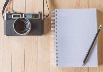 Retro film cameras and notebook on wooden background.