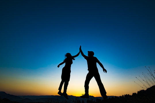 Girl and man holding for hands and jumping. They are successfull people.