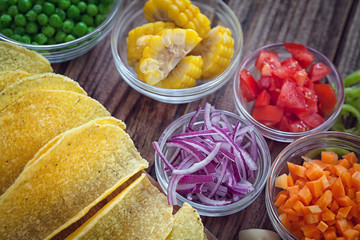 Mexican corn tortilla tacos with vegetables on wooden background