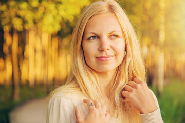 Young, beautiful, gentle woman walking in the park and looking at sunset.