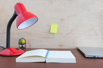 Metallic red lamp on the desk reading a book.