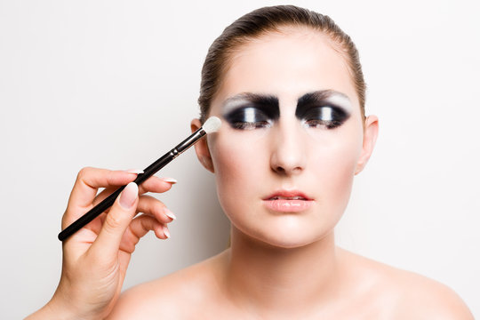 Young girl model with striking dark smokey eyes make up. The make up is applied with a brush, her eyes are closed.
