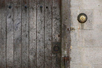 Old rusty metal ring handle on a aged timber door with brass doo
