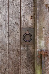 Old rusty metal ring handle on a aged timber door