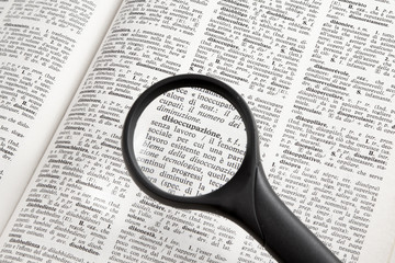 Una lente d'ingrandimento sopra un vocabolario evidenzia la parola "disoccupazione".