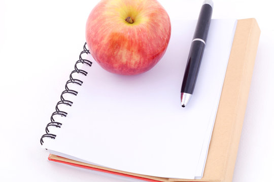An apple on a notepad against white background.