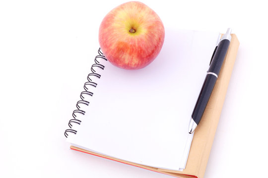 An apple on a notepad against white background.