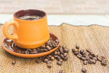 black coffee in brown cup pottery and roasted coffee beans on ta