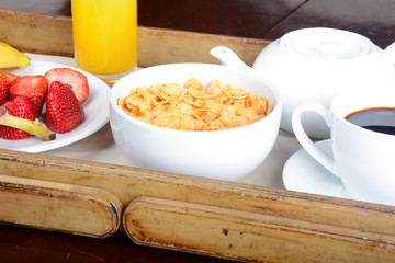 Breakfast tray with coffee, orange juice, cereals and fruits.