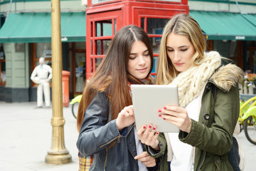Two young girlfriends on a trip together and using the tablet.