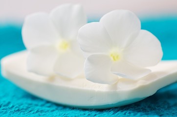 Fototapeta na wymiar Weiße Seife mit Blüten auf türkisem Handtuch