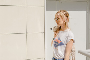 stylish girl with long hair dyed in the yard on the street, dressed in blue jeans and a white...