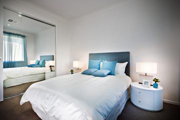 Bed with a huge mirror beside a lamp and table