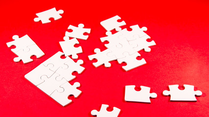 solving the puzzle, still life with a white jigsaw/puzzle incomplete over a red background, symbol of problem solving
