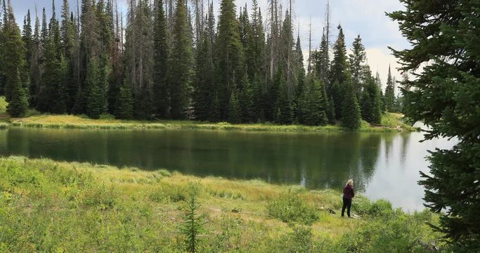 Woman fishing shore of mountain forest lake. Beautiful clear water mountain lake. Nature in natural environment. Recreation, hiking, and fishing ponds. Potter's Pond. Campground destination.