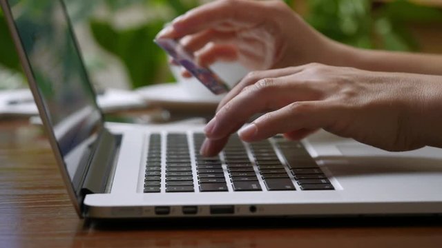 Shopping online concept. Woman hands holding credit card and using laptop.  High quality shot, UHD, 4K
