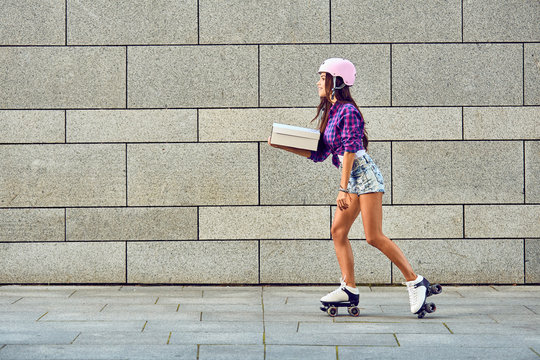 Fast delivery of sportive girl on roller skates. Young woman on roller skates with box or pizza in hands.