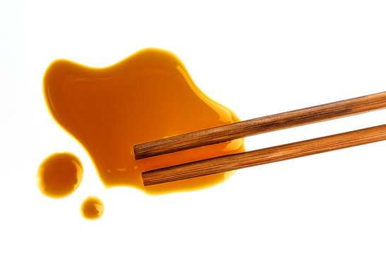 Soy sauce and chopsticks on white background