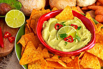 Classic Homemade avocado hummus with olive oil, carrots, pita chips, lime, chilli, parsley.