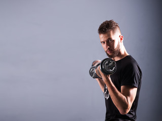 One white attractive man raising a dumbbell. Free spase for comercial Grey background with room for text