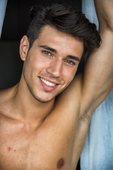 Fototapeta premium Sexy handsome young man standing shirtless in his bedroom next to window curtains