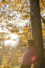Woman in pink sweater leaning against tree
