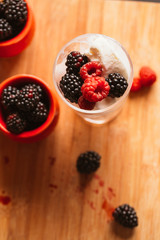 Blackberry ice cream in a cup and  glass on  background of wooden boards   blurred green