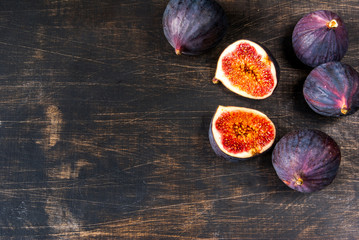 Ripe raw figs on a black wooden table, top view, copy space